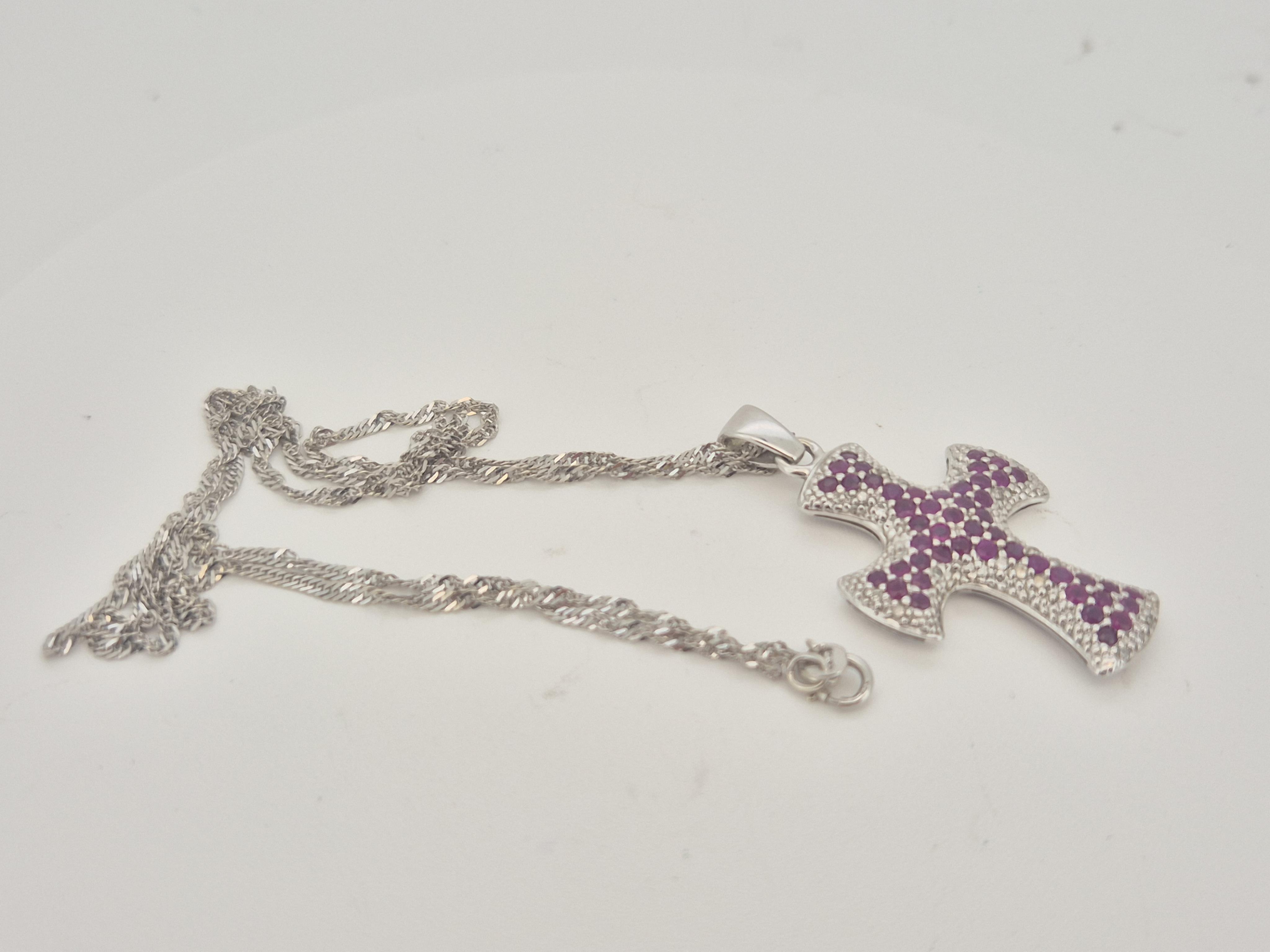 A modern 9ct white gold, ruby and diamond chip cluster set cross pendant, overall 37mm, on a 9ct white gold chain, approx. 44cm, gross weight 7.3 grams.